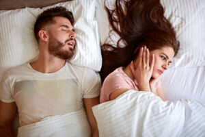 man in bed snowing while woman covers her ears