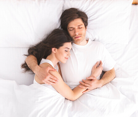 Couple asleep on white bed
